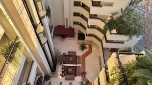 Ein mehrgeschossiges Atrium mit einer zentralen Sitzecke, umgeben von Balkonen und Treppenhäusern.