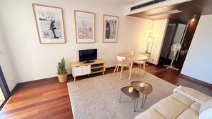 A modern living room with a wooden floor, a beige sofa, a coffee table, a TV stand, and framed artwork on the wall. - Ocean view condo with terrace, garage and swimming pool in center of Cascais (Cascais)