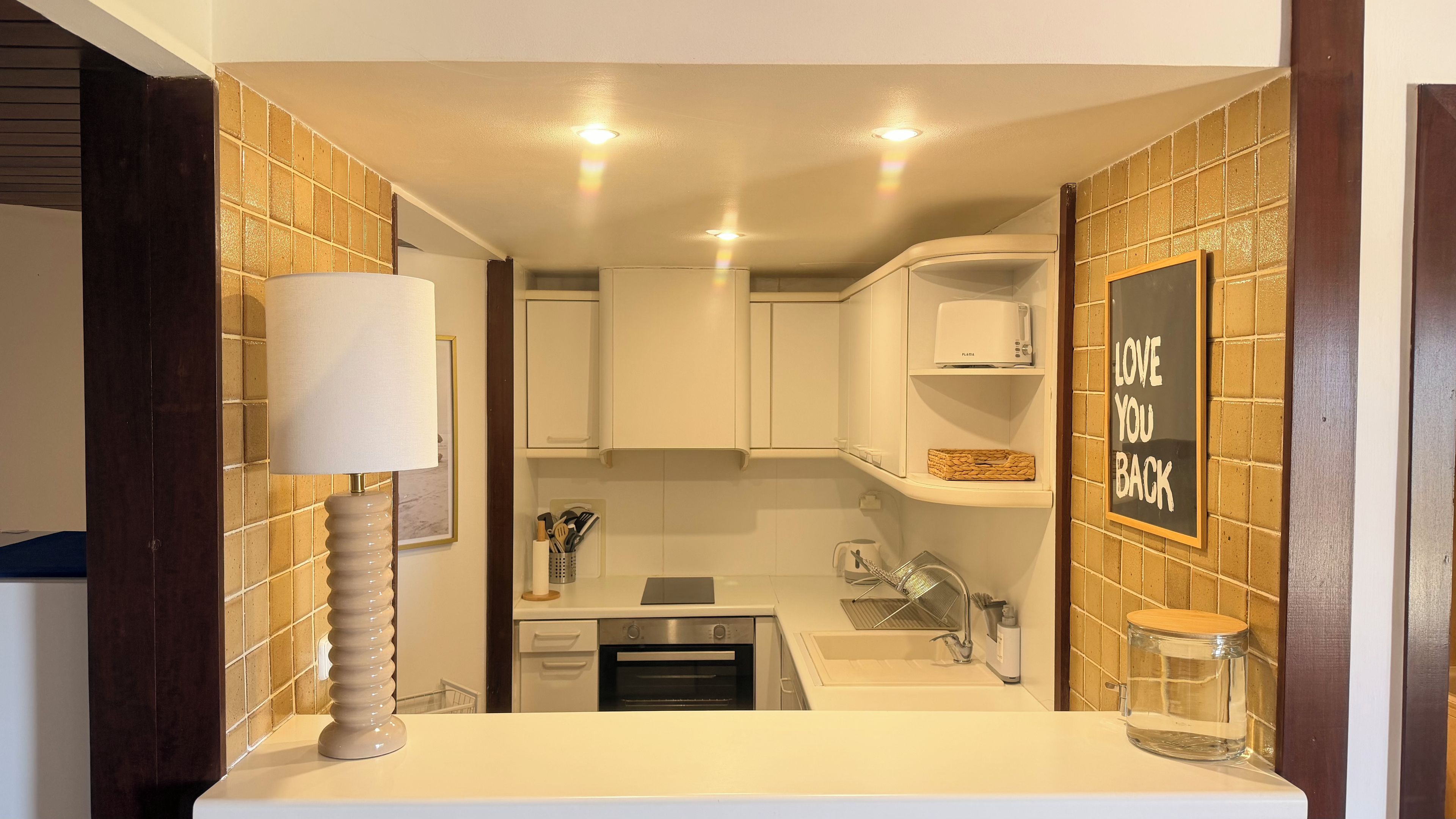 A modern kitchen with white cabinets, a built-in oven, and a countertop with a sink.