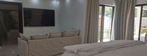 Une chambre d’hôtel avec un lit, un canapé, un téléviseur fixé au mur et une vue sur l’extérieur.