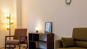 A living room with a sofa, a chair, a floor lamp, and a bookshelf. - Hygge Living Lisbon-Belém Long Stay (Lisboa)