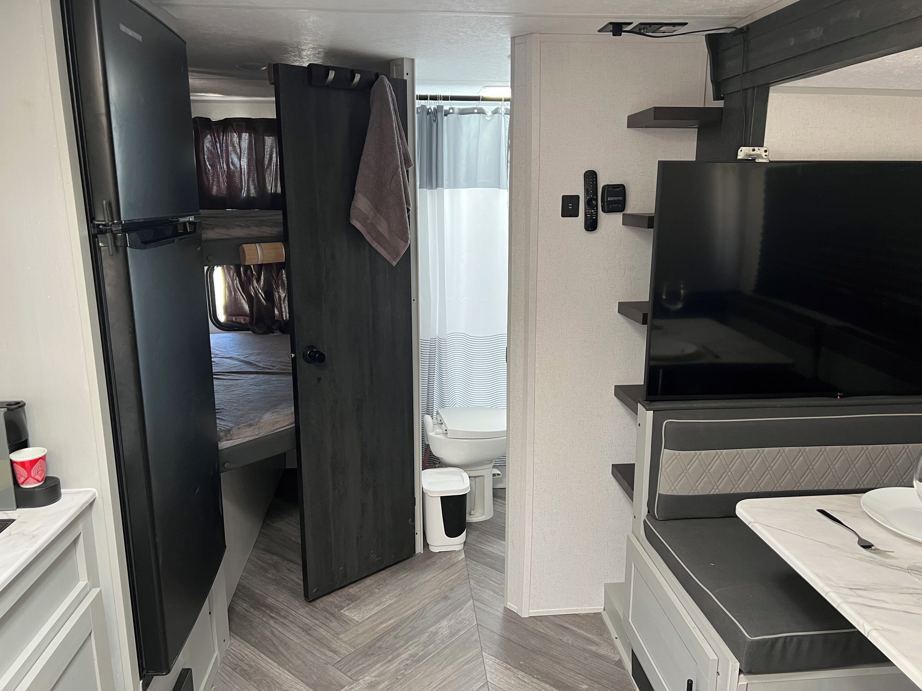 Een ruimtelijk ingerichte camper met een kitchenette, een bed, een badkamer en een televisie.