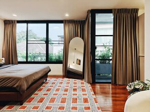 Une chambre à coucher avec un lit, un tapis à motifs, une vue sur l’extérieur et des rideaux.