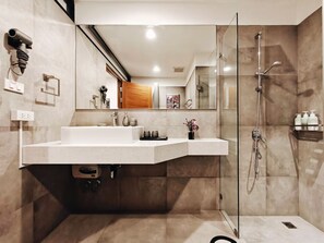 Une salle de bain moderne avec une douche à parois de verre, un meuble-lavabo blanc doté d’un miroir et un luminaire encastré dans le plafond.