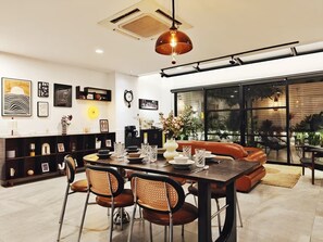 Un espace repas moderne avec une table en bois foncé, des chaises en cuir et un luminaire suspendu.