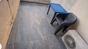 A tiled patio with a blue table and a black plastic chair. An LG air conditioner is visible. - Cozy & Convenient 1-Bedroom in Vibrant Victoria Island, Lagos (Lagos)