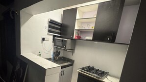 A compact kitchen with a gas stove, microwave, and black cabinets. - Cozy & Convenient 1-Bedroom in Vibrant Victoria Island, Lagos (Lagos)