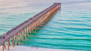A long pier extending into the ocean with people walking along it.
