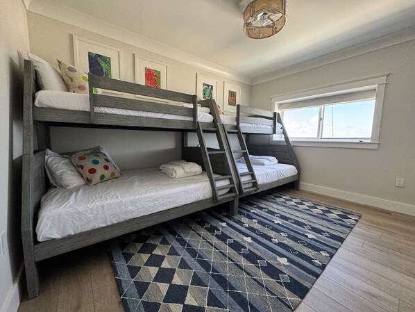 Habitación con literas, alfombra estampada, suelo de madera y cuadros en la pared.