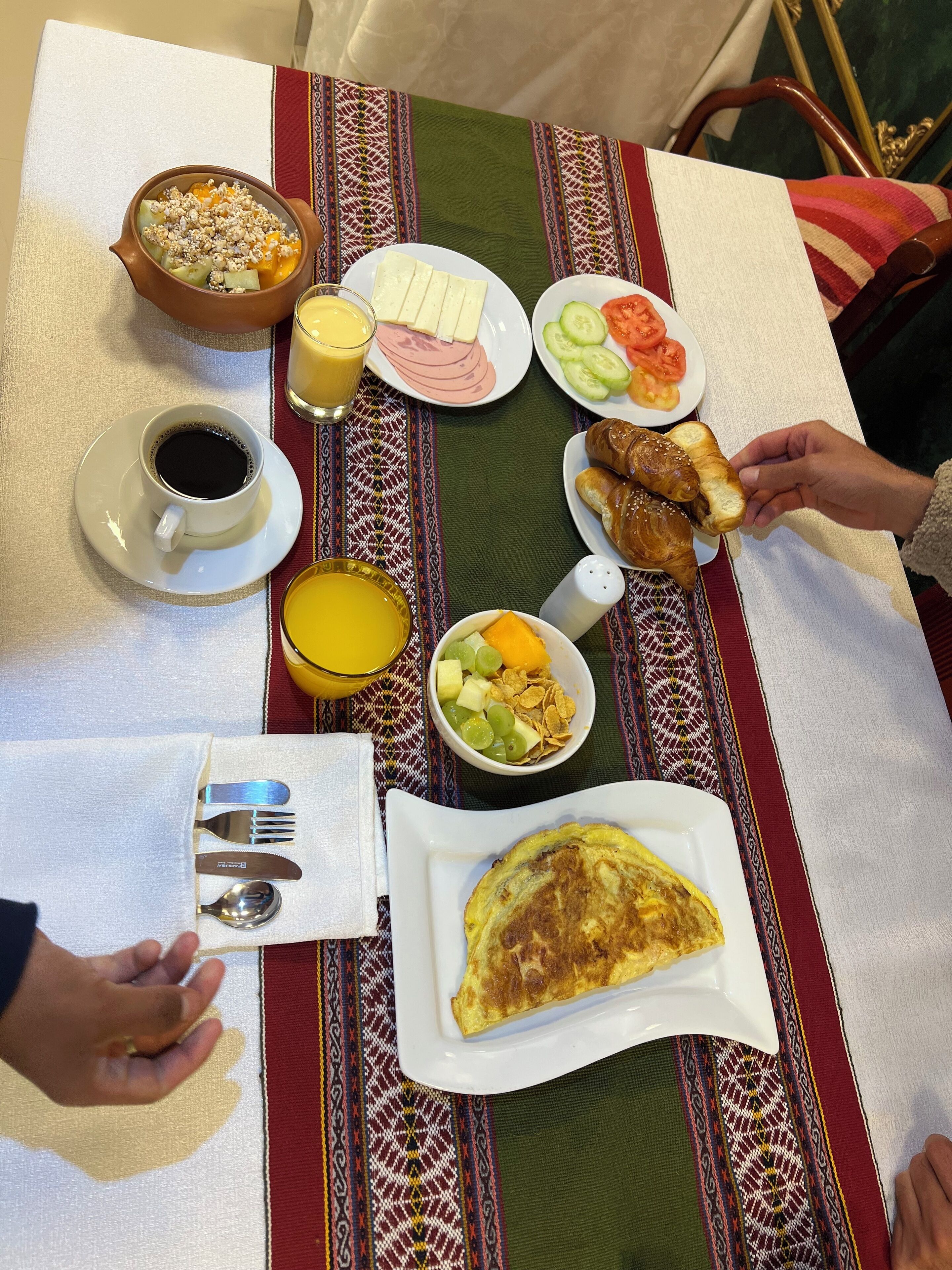 Una mesa de desayuno con diversos platos, incluyendo tostadas, fruta y una fuente de huevos revueltos.