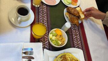 Una mesa de desayuno con diversos platos, incluyendo tostadas, fruta y una fuente de huevos revueltos.