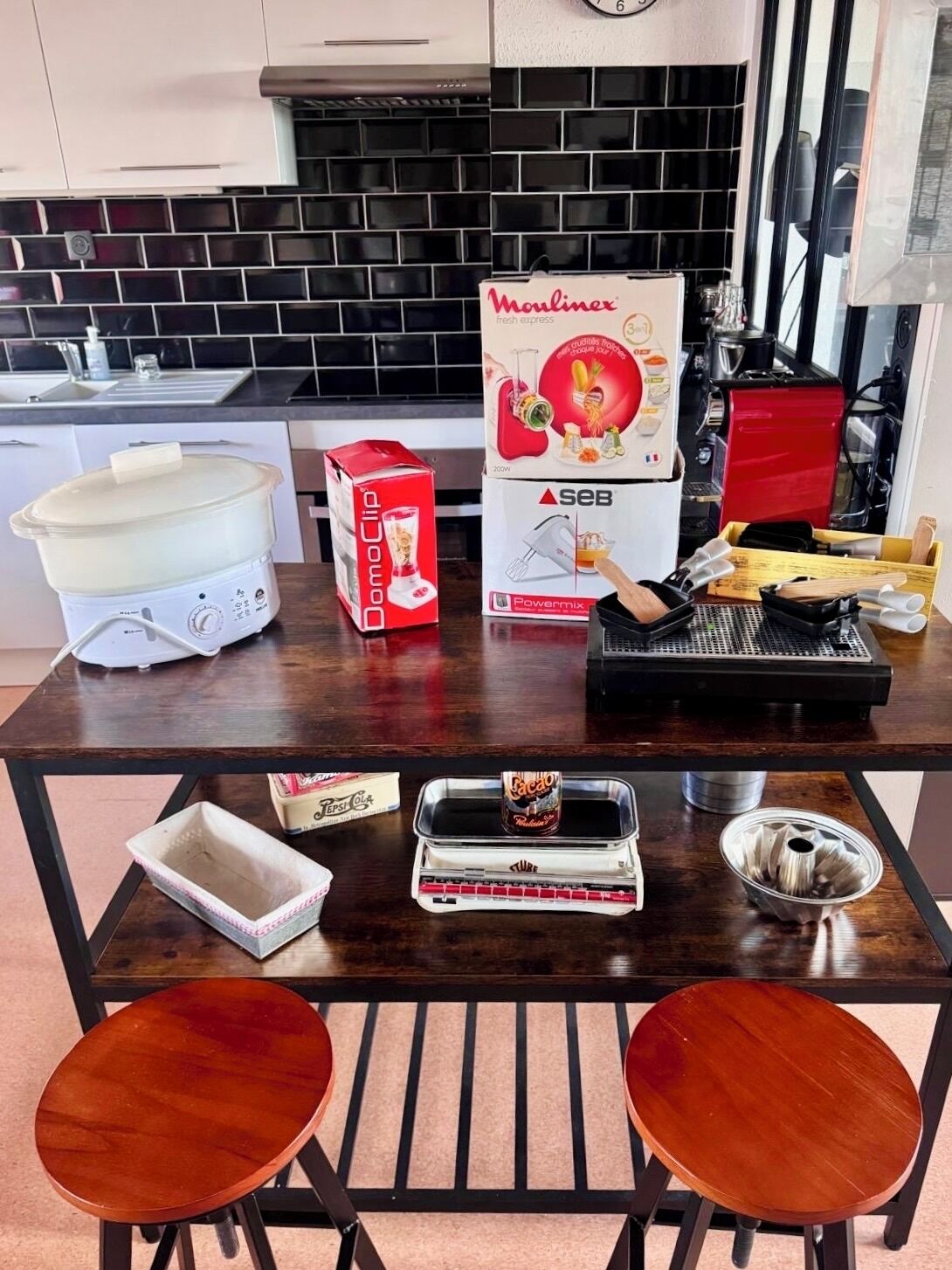 Uma cozinha com fogão, máquina de café, uma caixa de DomoClip, uma caixa de Powermix e uma lata de Coca-Cola.