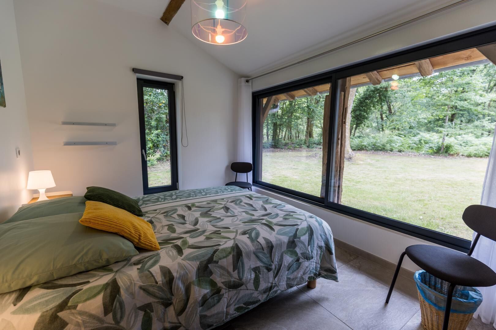 Une chambre à coucher avec un lit, une chaise, une fenêtre et une vue sur l’extérieur.