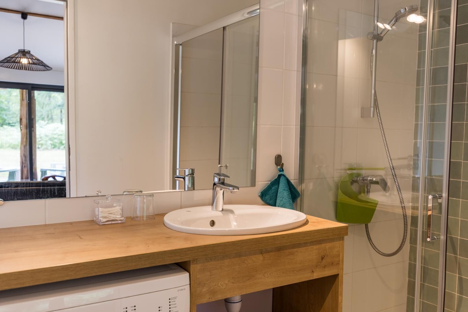 A bathroom with a wooden vanity, a white sink, a mirror, and a glass shower enclosure.