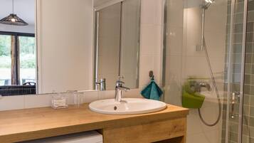 A bathroom with a wooden vanity, a white sink, a mirror, and a glass shower enclosure.