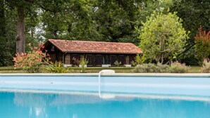 A swimming pool with a wooden building in the background. - Gîte du Caché - LABRIT - Gîte (LABRIT)