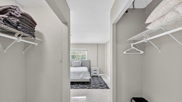 A narrow hallway with a bed, a small bedside table, and a window with a view of greenery.