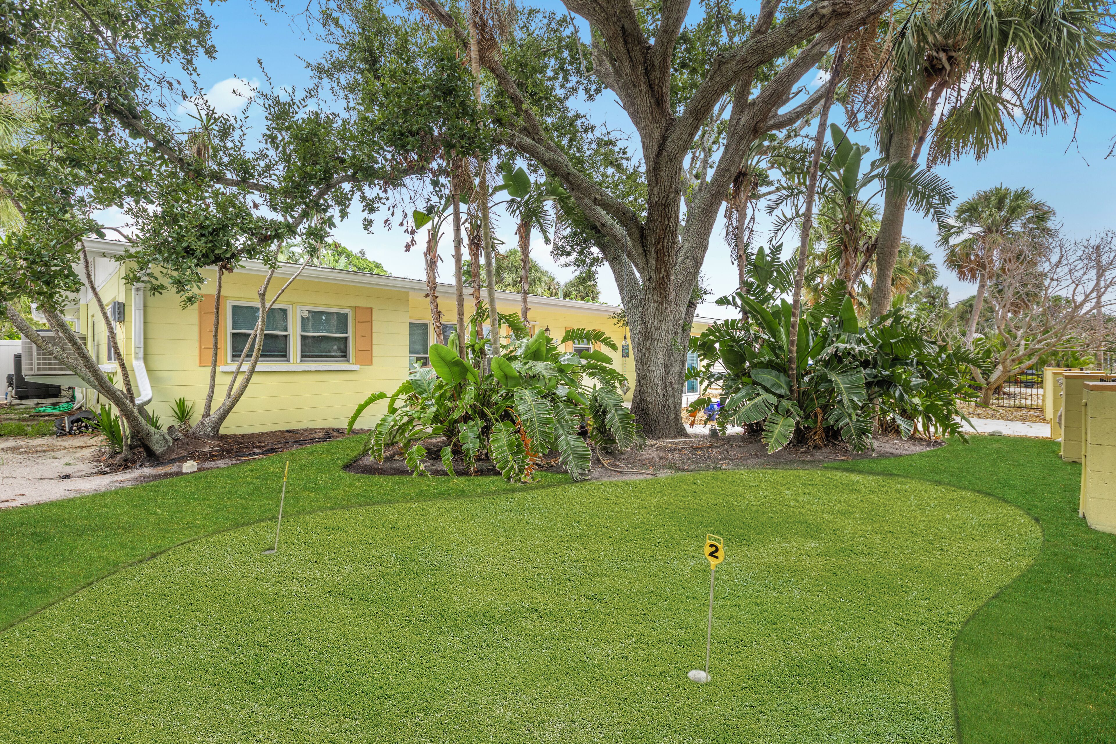 A residential property with a well-maintained lawn, a golf hole, and mature trees.