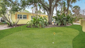 A residential property with a well-maintained lawn, a golf hole, and mature trees.