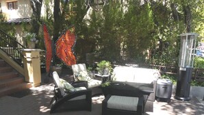 Terrasse mit Tisch und Stühlen, umgeben von Bäumen und einer Treppe.