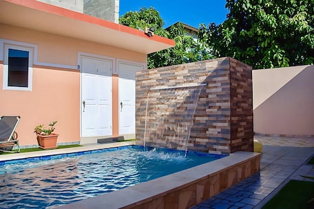 Una piscina al aire libre, sombrillas, sillones reclinables de piscina