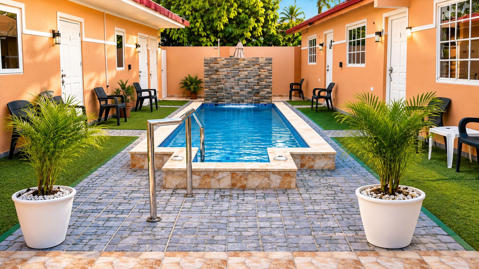 A swimming pool with a stone wall, surrounded by potted plants and outdoor furniture.