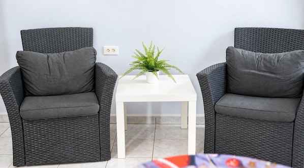 Two grey wicker chairs with cushions, a white table with a plant, and a tiled floor. - Sunway Aruba Aparments (Santa Cruz)