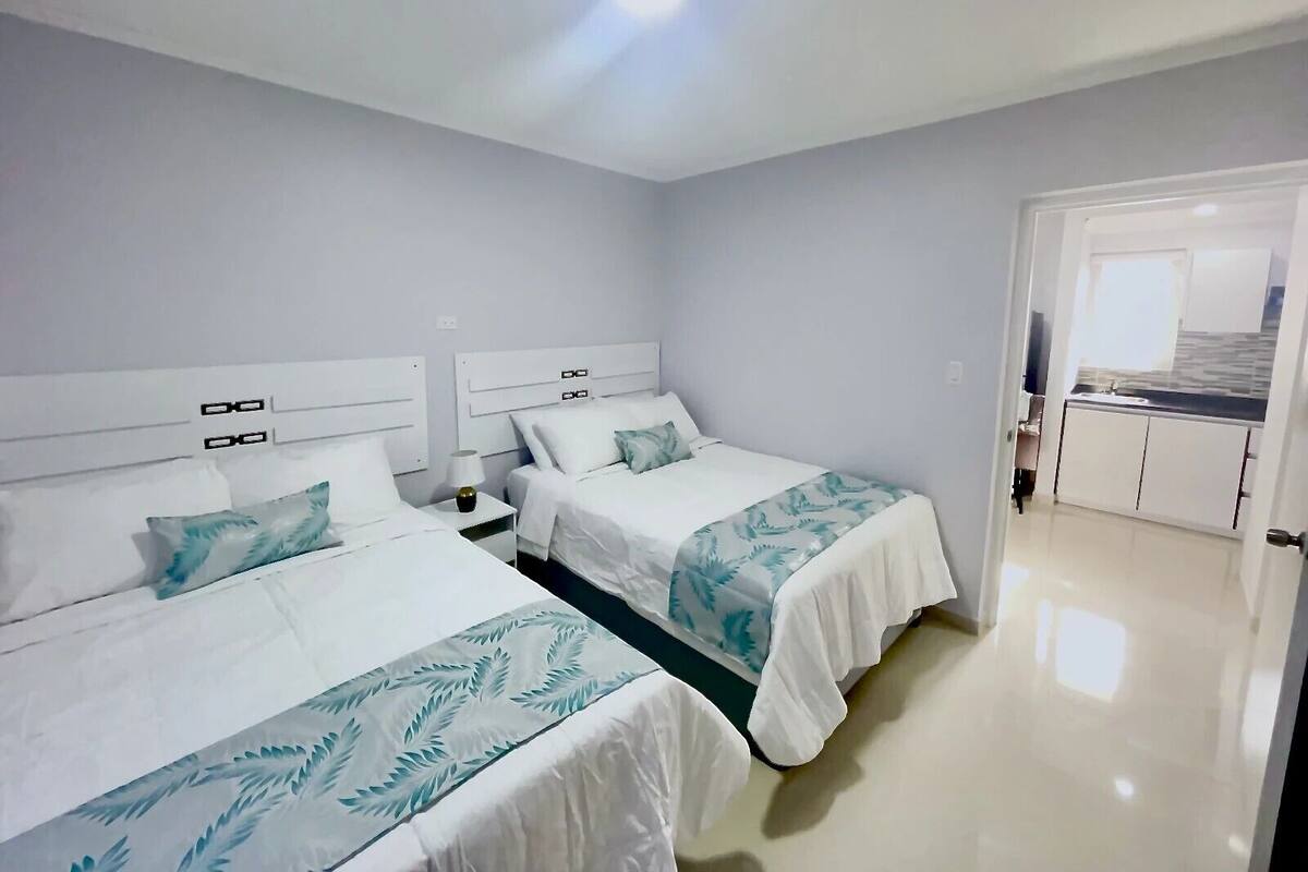 Habitació d'hotel amb dos llits, una cuineta i un bany.