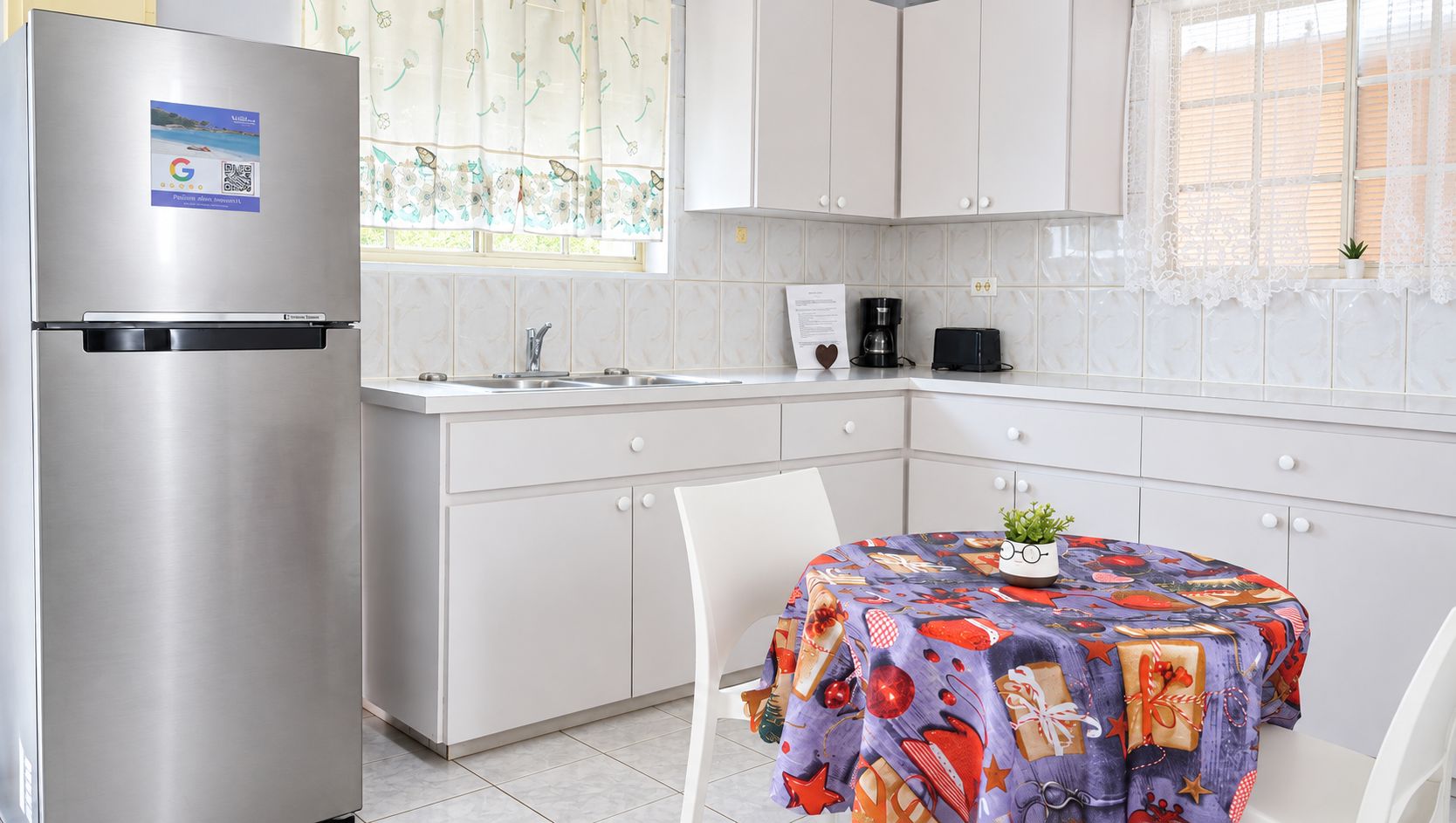 A modern kitchen with a stainless steel refrigerator, a sink, and a dining table with a colorful tablecloth.