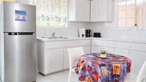 A modern kitchen with a stainless steel refrigerator, a sink, and a dining table with a colorful tablecloth. - Sunway Aruba Aparments (Santa Cruz)