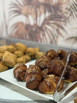 Un piatto di pasticcini, tra cui croissant e altri prodotti da forno, su una superficie in marmo.