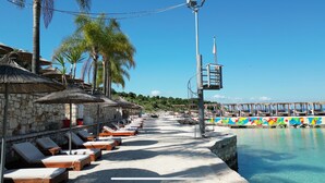 A beachside resort with lounge chairs, thatched umbrellas, and a pool area. - Mucobega Hotel  (Sarande)