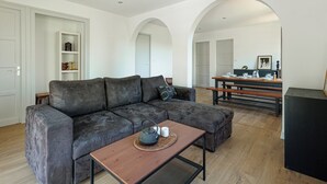 A modern living room with a grey sectional sofa, a wooden coffee table with a teapot, and a bookshelf. - Appartement Prunelle - Welkeys (Soorts-Hossegor)