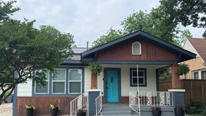 Une maison de plain-pied avec un porche à l’avant, une porte bleue et une boîte aux lettres.
