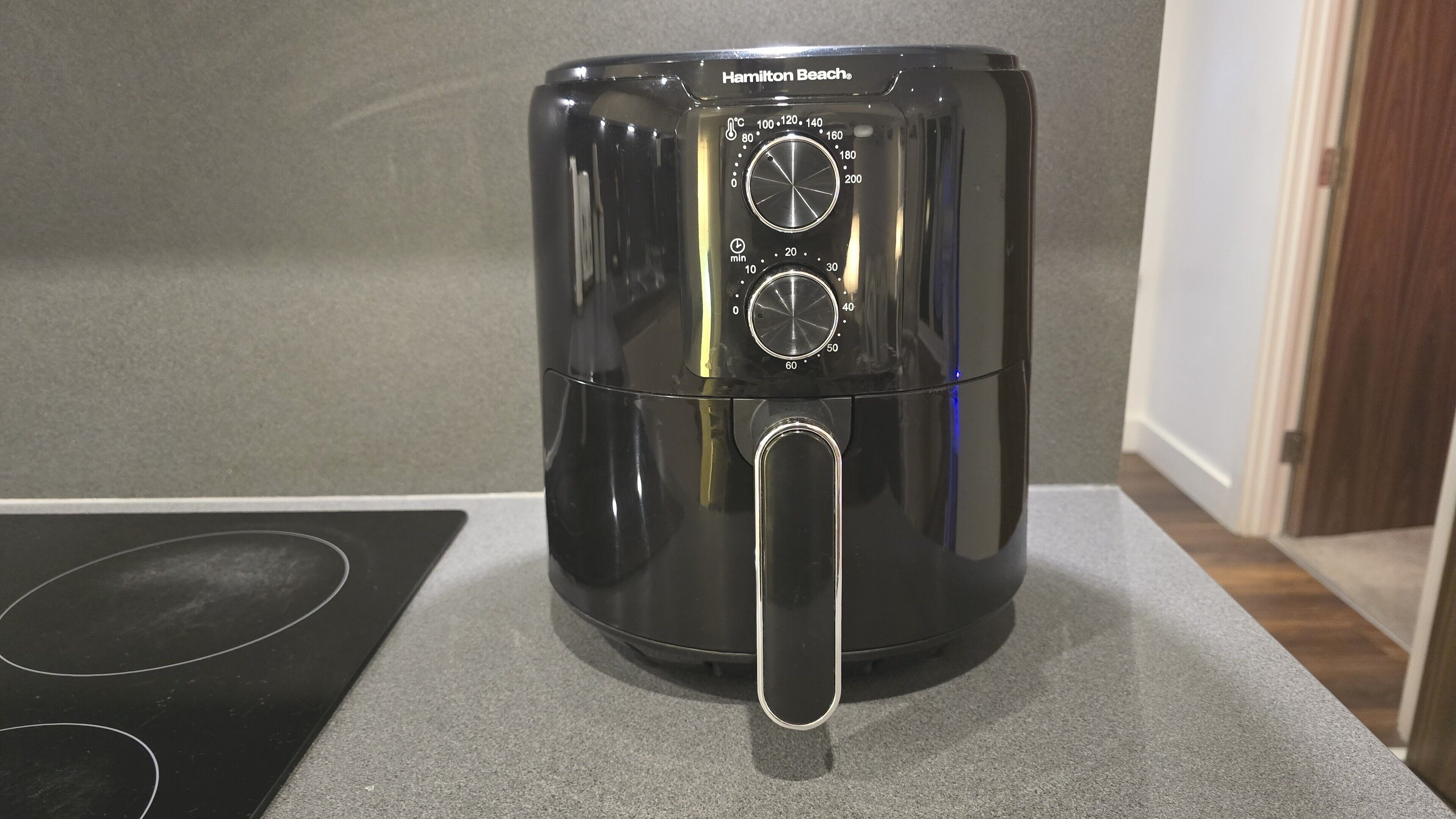 Een Hamilton Beach heteluchtfriteuse op een aanrecht, met een bedieningspaneel waarop temperatuur en timerinstellingen staan.