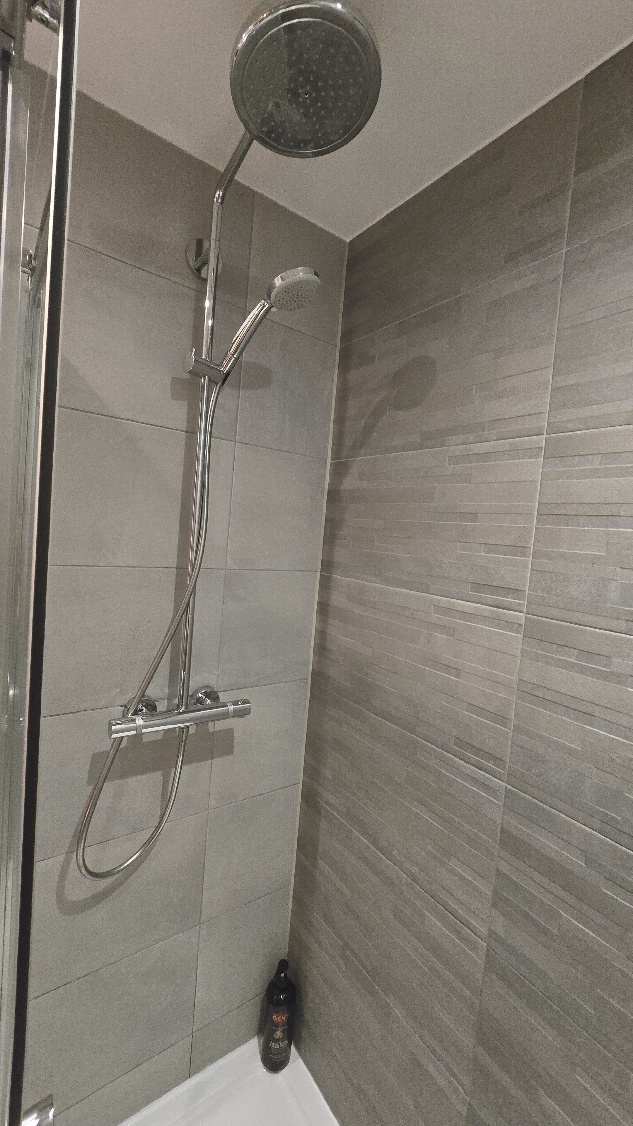 Een douche met een handdouche en een wandmengkraan.
