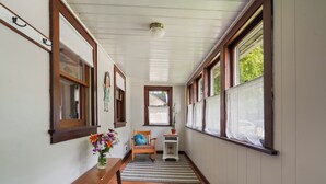 A hallway with wooden floors, a bench, a chair, and a small table with a vase of flowers. - Charming 2-bedroom house in Viroqua with AC (Viroqua)