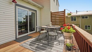 A patio with a table and chairs, a wooden deck, and a sliding glass door leading to a covered area. - Charming 2-bedroom house in Viroqua with AC (Viroqua)
