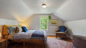 A bedroom with a bed, a chair, a window, and a hanging plant. - Charming 2-bedroom house in Viroqua with AC (Viroqua)