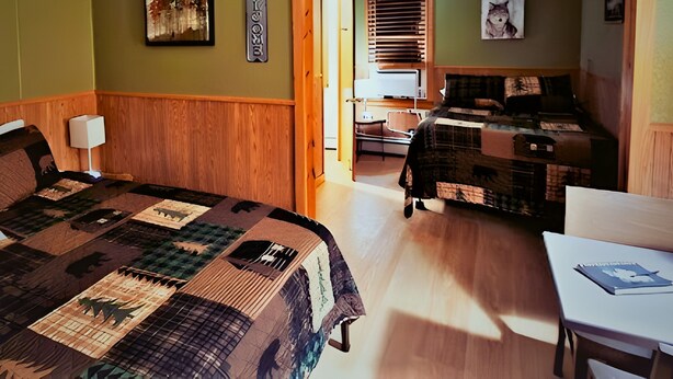 Una habitació amb un llit gran, un escriptori i una cadira. Hi ha un quadre a la paret i una finestra amb persianes.