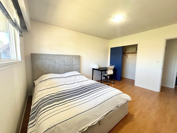 A bedroom with a bed, a desk, and a chair.