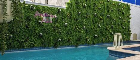 Ein Poolbereich mit grüner Wand und einem Schild mit der Aufschrift 'Santorini Hotel'.