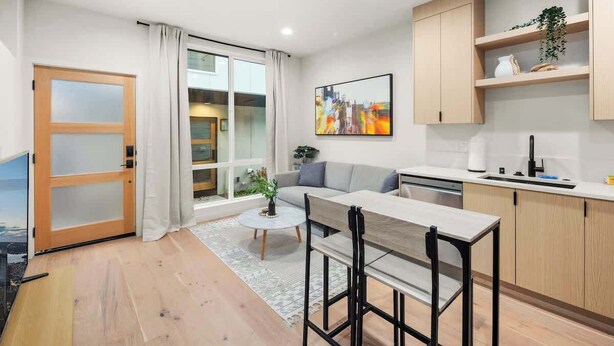 A modern apartment with a dining area, kitchen, and a large sliding glass door leading to a balcony.