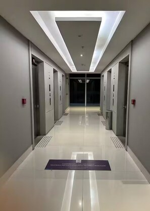 A modern, well-lit hallway with elevators and a reflective floor.