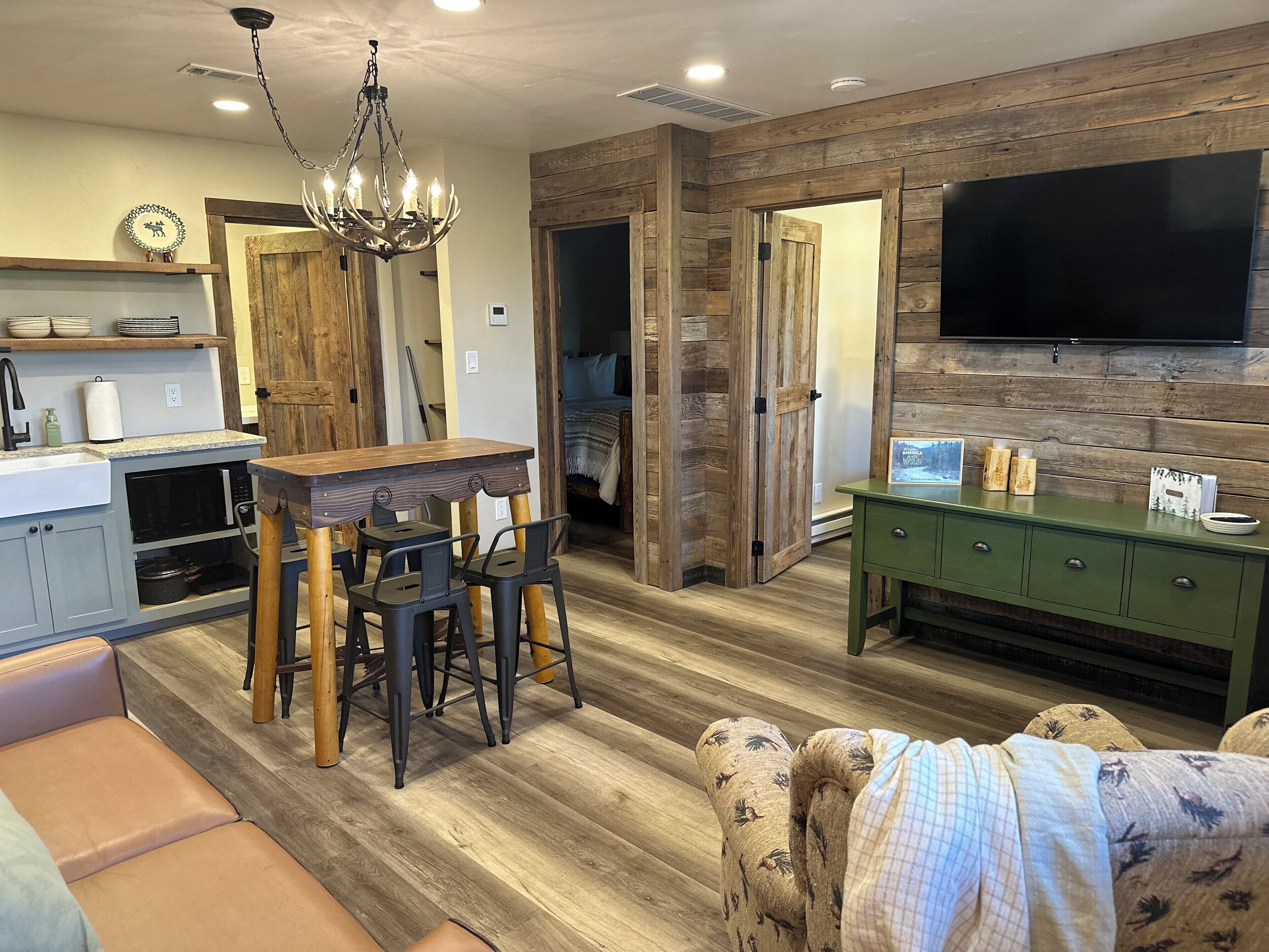 A modern kitchen with a dining area, wooden walls, and a flat-screen TV.