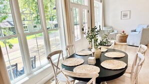 Un coin repas avec une table ronde, des chaises blanches et des sets de table en fibres tressées.
