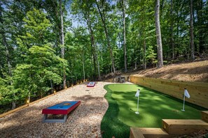 A golf course with a putting green, sand bunkers, and a wooden fence. - Cavalier Cabin - Pet Friendly | Hot Tub | Mountain View | Game Room (Blue Ridge)
