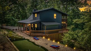 A log cabin with a porch, a deck, and a small pool area.