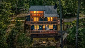 Une cabane à deux étages avec une terrasse, entourée de forêt.