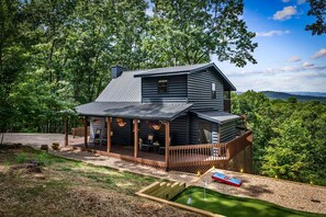 A cabin with a porch, a deck, and a small garden area.